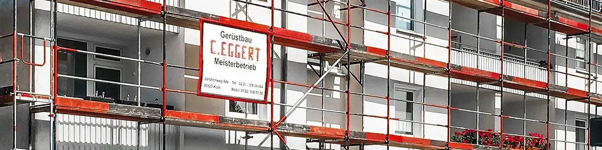 Firmenschild „Gerüstbau C. Eggert Meisterbetrieb“ an einem eingerüsteten Wohnhaus