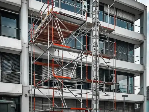 Ein im Bau befindliches Gebäude mit Gerüst und einem Aufzug davor.