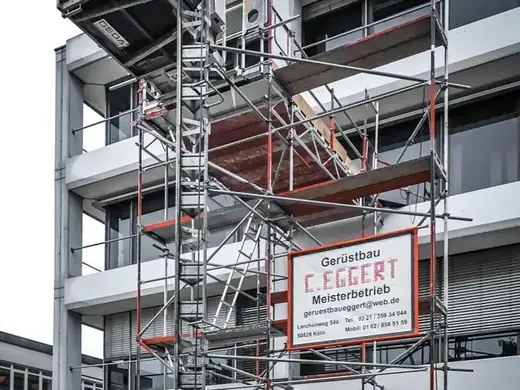 Mit Gerüst und Kran wird ein Gebäude errichtet.