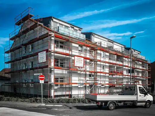 Ein weißer Lastwagen parkt vor einem im Bau befindlichen Gebäude.