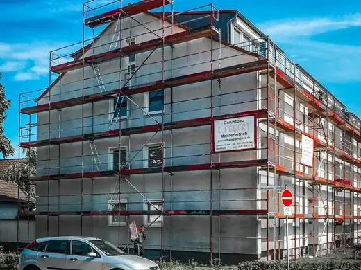 Ein Auto ist vor einem im Bau befindlichen Gebäude geparkt.