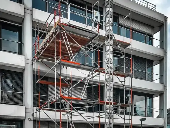 Ein im Bau befindliches Gebäude mit Gerüst und einem Aufzug davor.